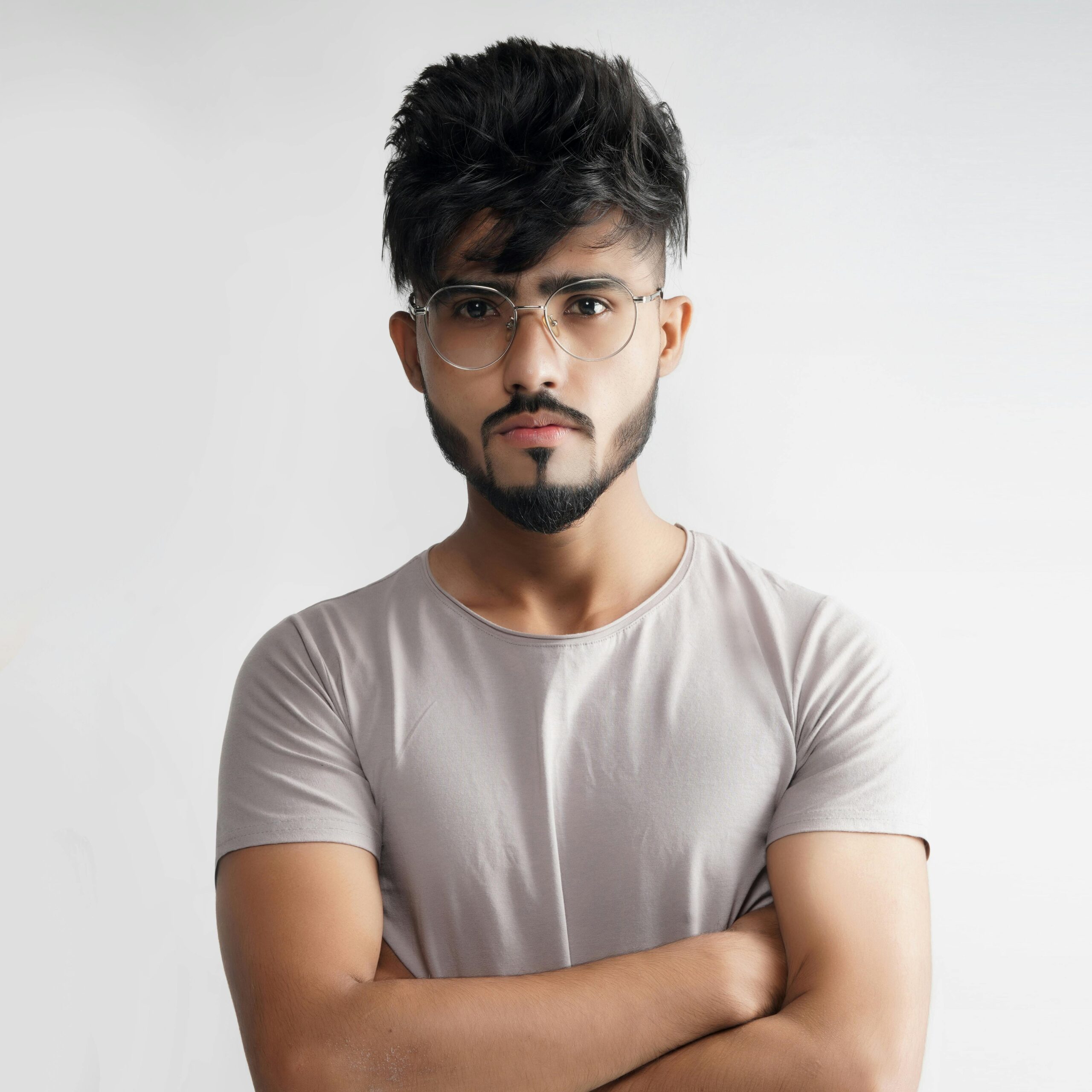 Portrait of a man with glasses and beard, arms crossed against a white background.